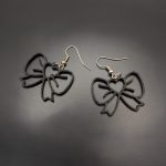 Black open bow dangle earrings with fish hook fastenings displayed on a dark background.
