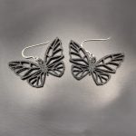 Black butterfly statement earrings featuring an intricate open-wing design with silver hooks.