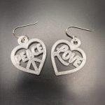 Heart-shaped Peace & Love statement earrings featuring peace and love lettering with silver hooks.