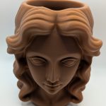 Brown Thinking Lady head planter with sculpted facial features, flowing hair and an open top for a small plant.