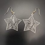 Star-shaped earrings featuring intricate flowing wave patterns suspended from silver fish hook fastenings.